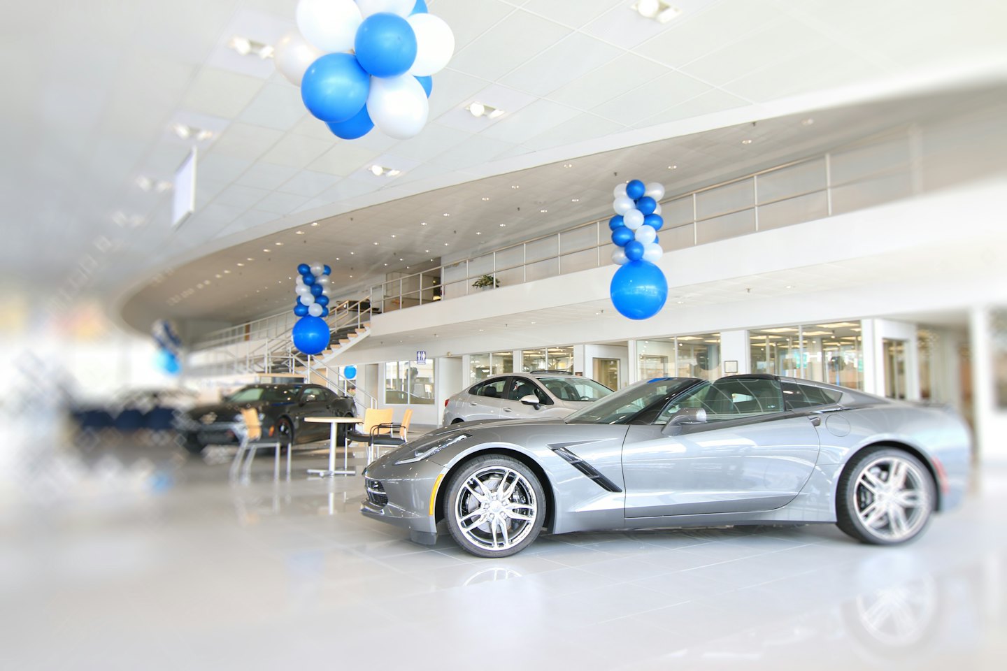 Lussuosa auto sportiva grigio metallizzato in un moderno showroom di concessionaria.